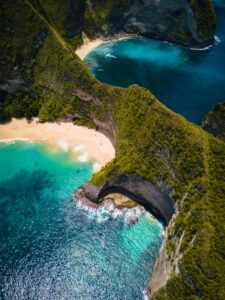 An aerial shot of the ocean surrounded by beautiful cliffs covered in greens